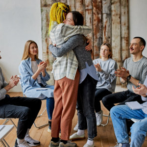 group of people sitting and two woman hugging each other